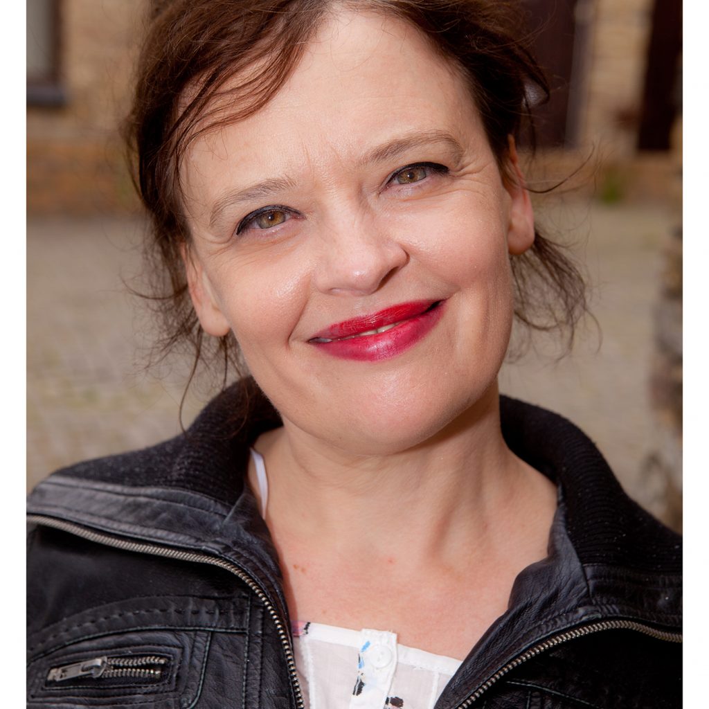 A woman in a black leather jacket smiles at the camera.