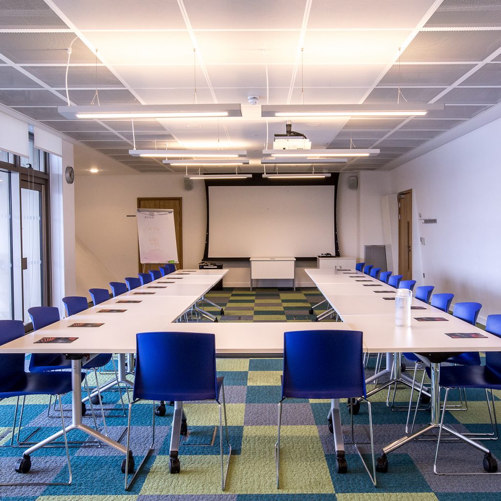 A large meeting room with tables in a U-shape and beautiful views of Canada Water.