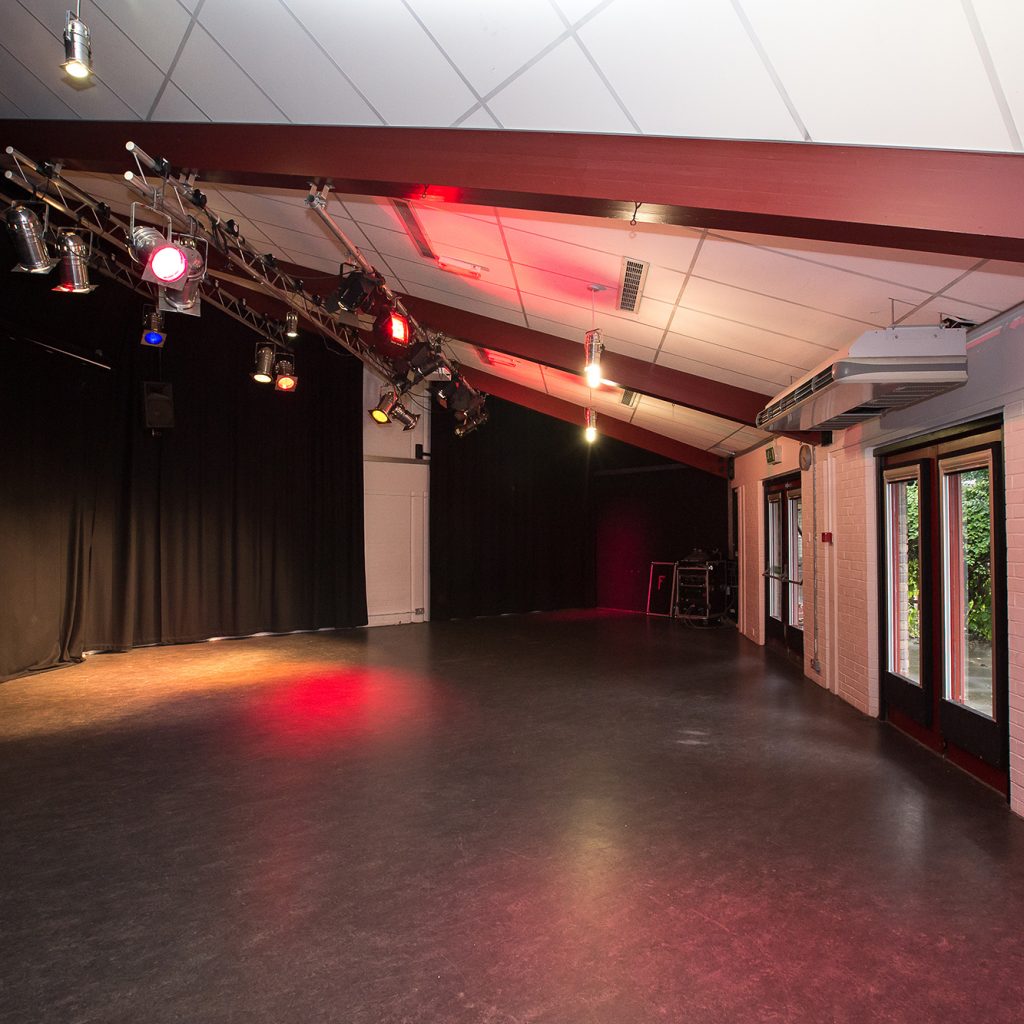 Studio with natural light and lighting rig and black floor.