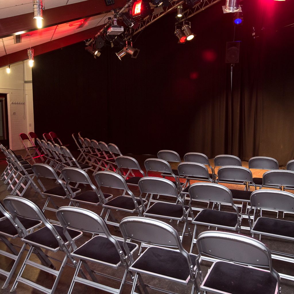 Rows of seats in a studio theatre with a black curtain at the back.