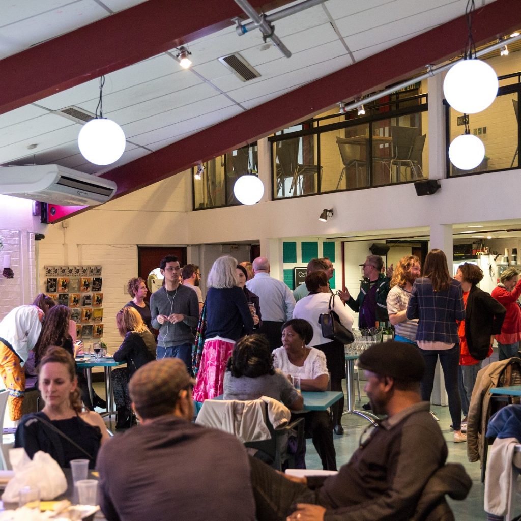 The Albany café with people eating, drinking and chatting, seated and standing.