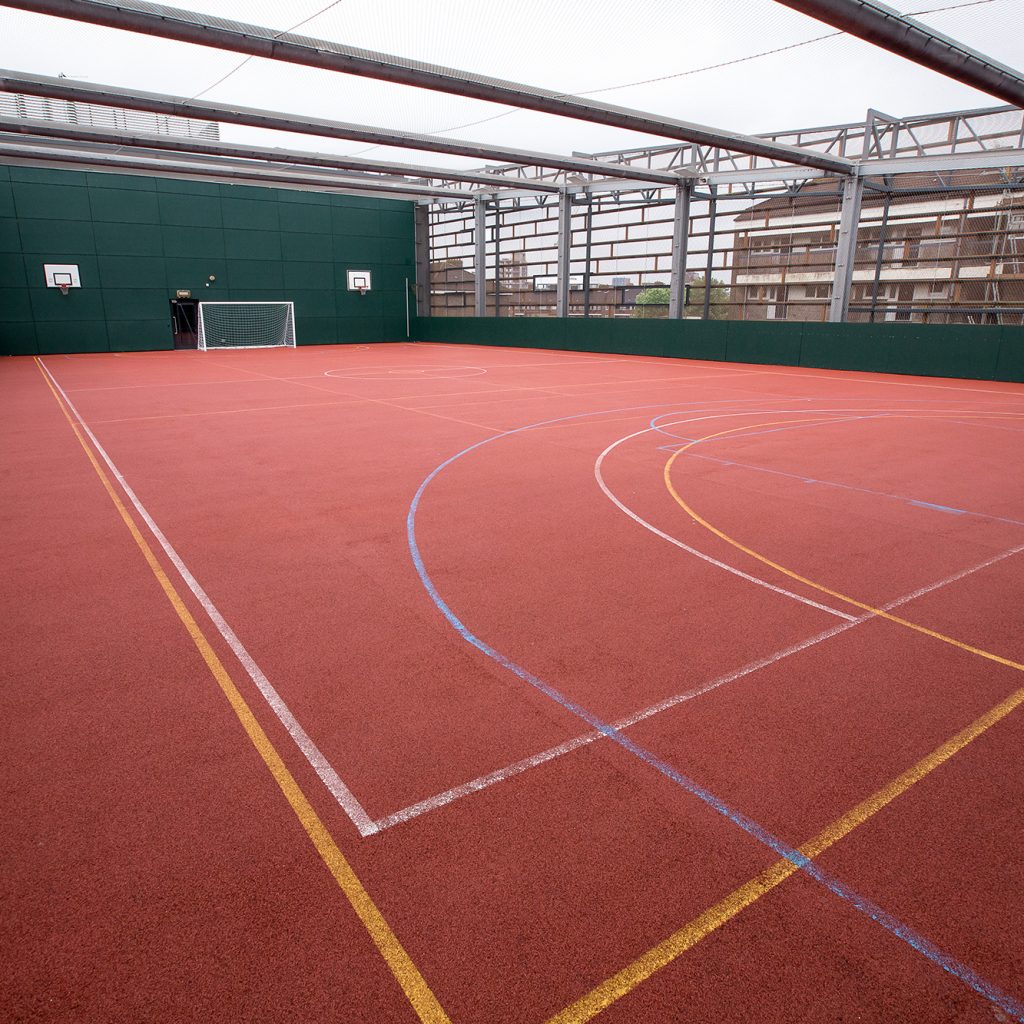 The rooftop Ballcourt at Deptford Lounge.: red ballcourt marked out with lines for sports with a football goal net at the far end.