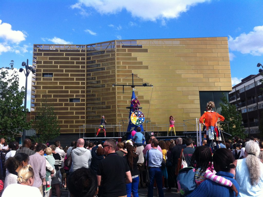 A large crowd of people on Giffin Square, outside a large gold building; Deptford Lounge.