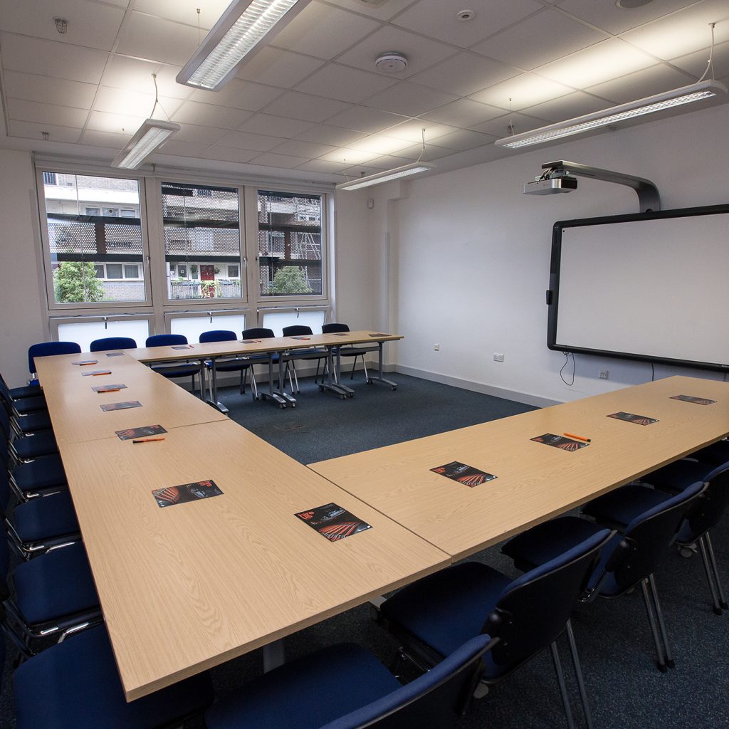 Meeting room with U-shapped table, window at the far end of the room and whiteboard at the front of the room.