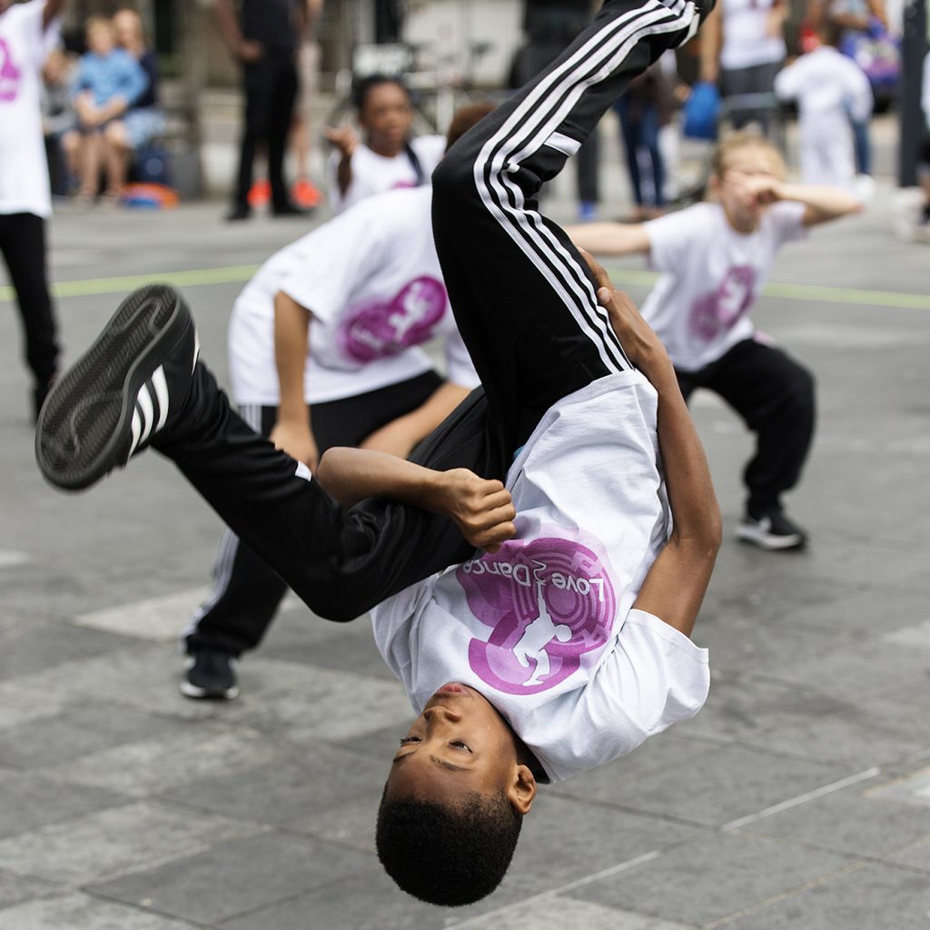 Young male dancer mid way through a backflip, outside on Giffin Square.