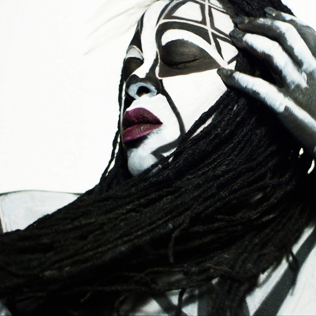 A Black woman with white paint on her face and hands