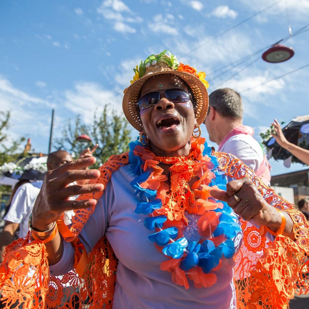 An older woman dressed to party in front of a blue sky.