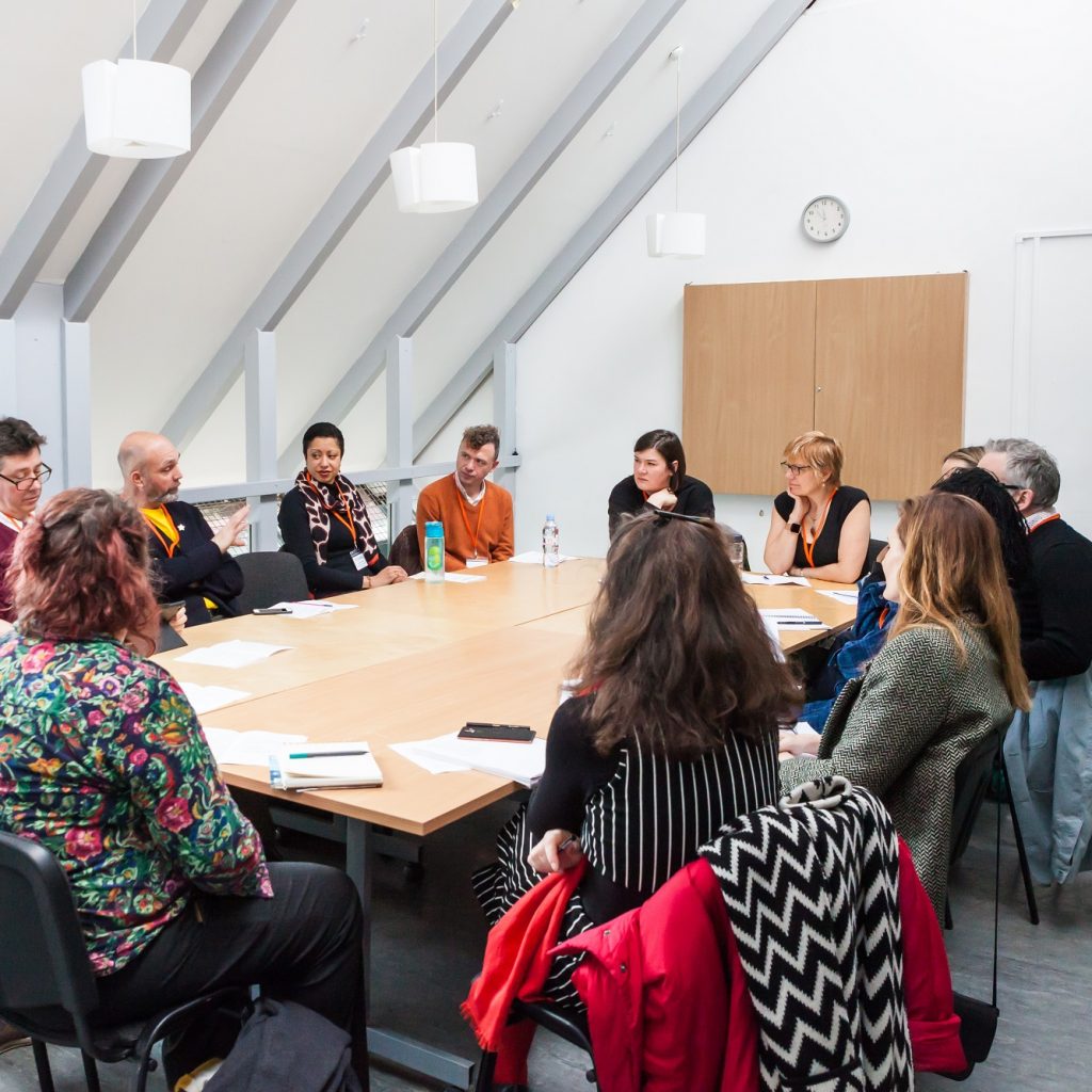 Group sat round a table in a bright meeting room