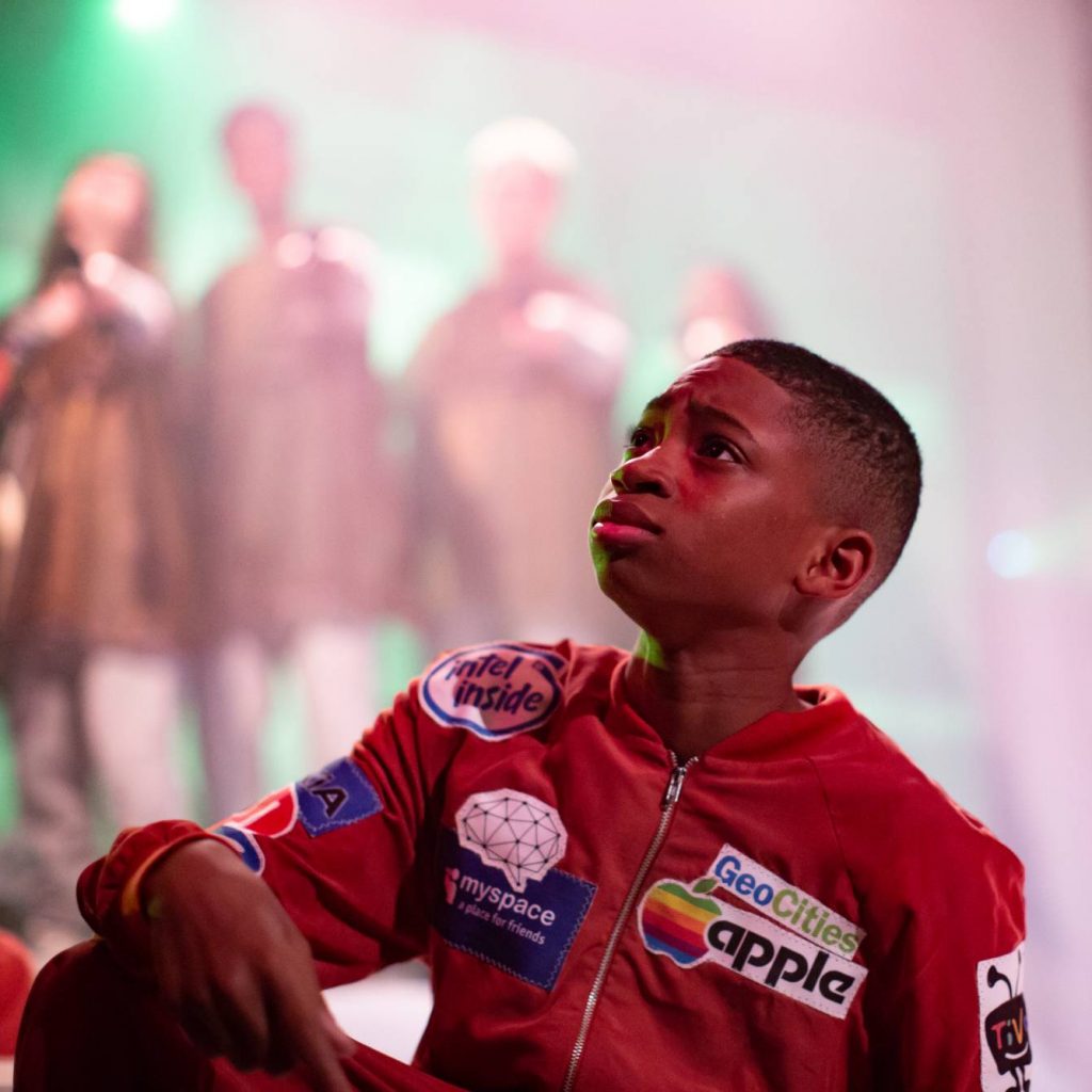 Image of a young boy in a red jacket, in profile looking upwards to the left