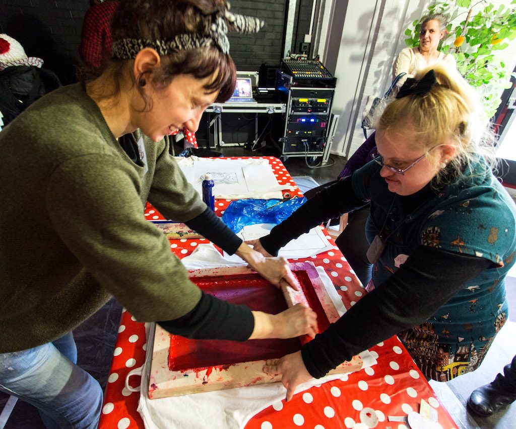 2 women working on a painting together.