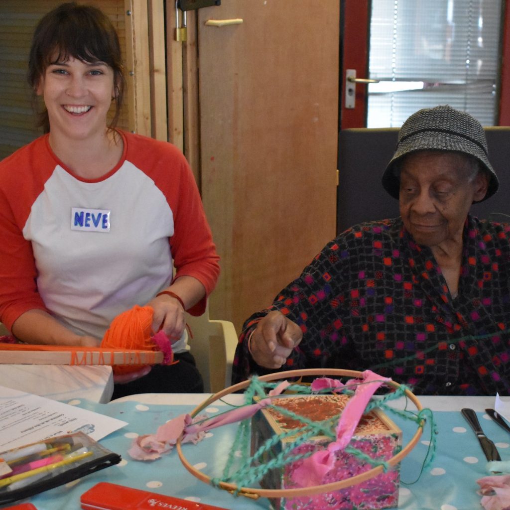 Younger woman and older woman sit together looking happy
