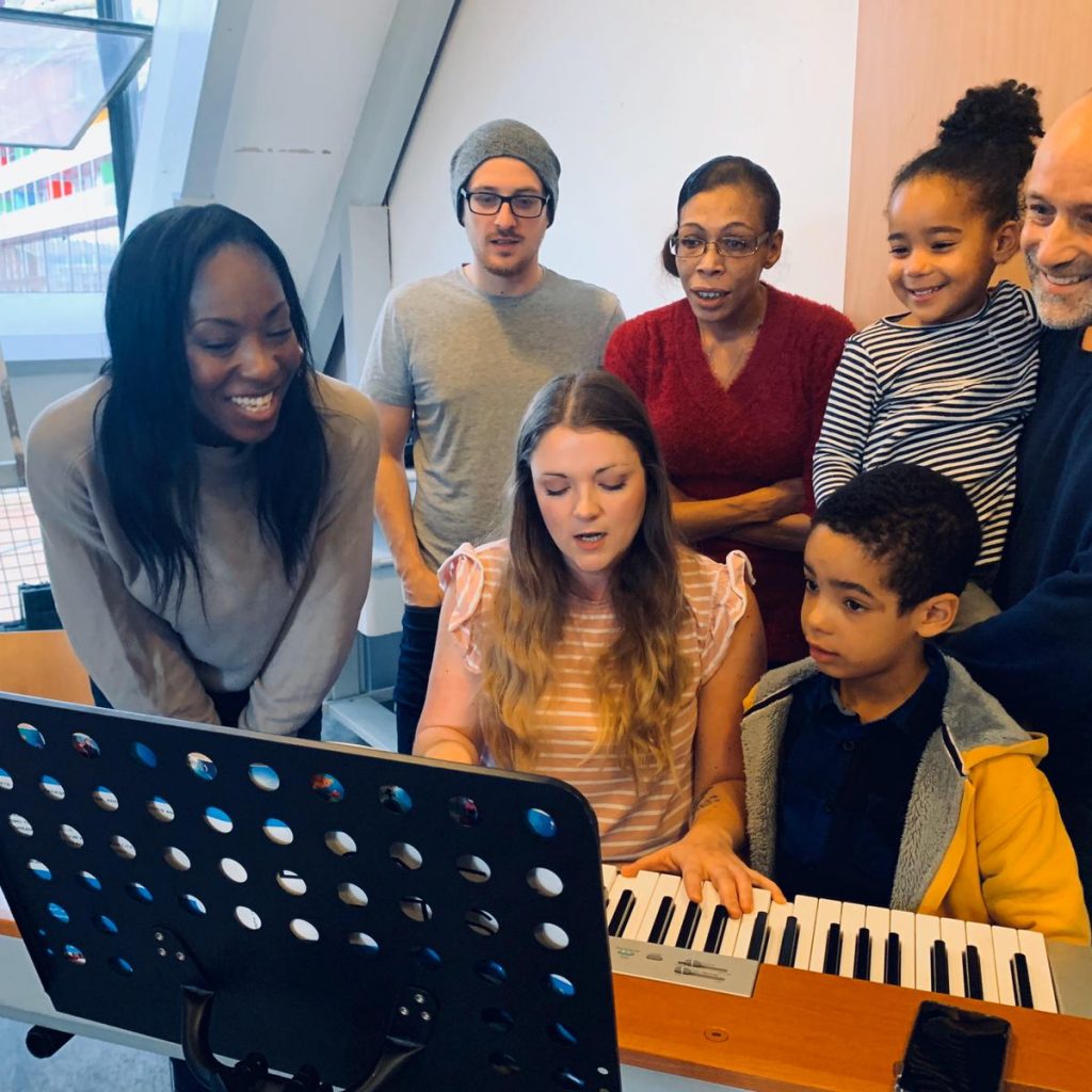 A group of of people sing in front of a keyboard