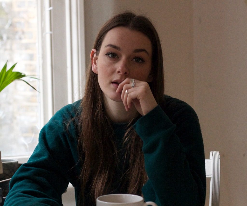 Image of a woman sitting at a table, biting her fingernail