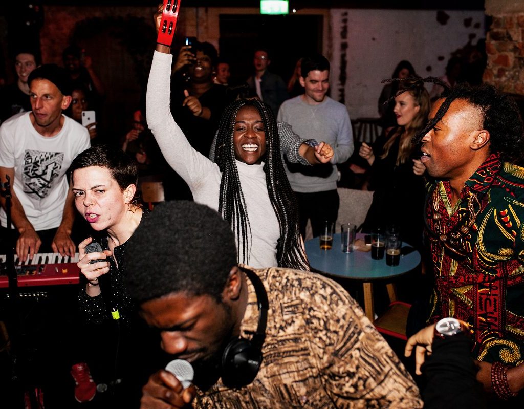 A group of young people dancing with hands in the air and instruments at a party