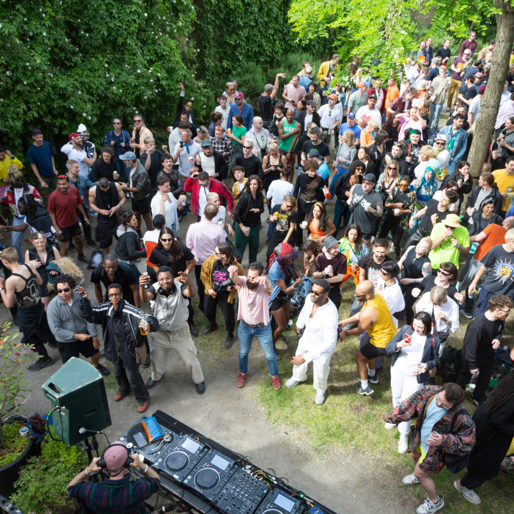 Photo taken from above of a large group of people stand in a garden.