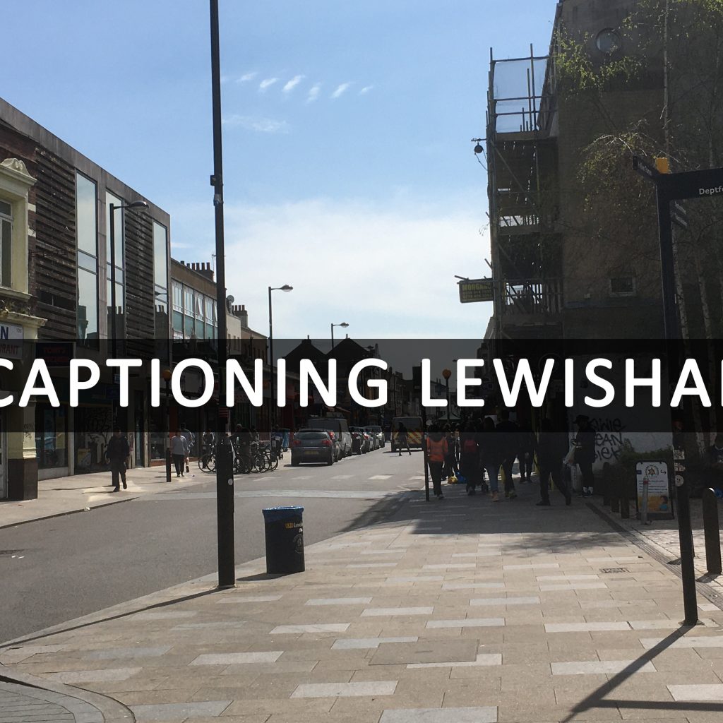 A photograph of an empty street on clear day. Text reading [Captioning Lewisham] is displayed across the photograph.