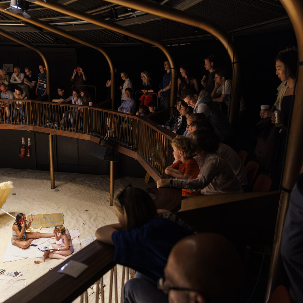 People on the Albany auditorium balcony looking down at the cast members of Sun & Sea.