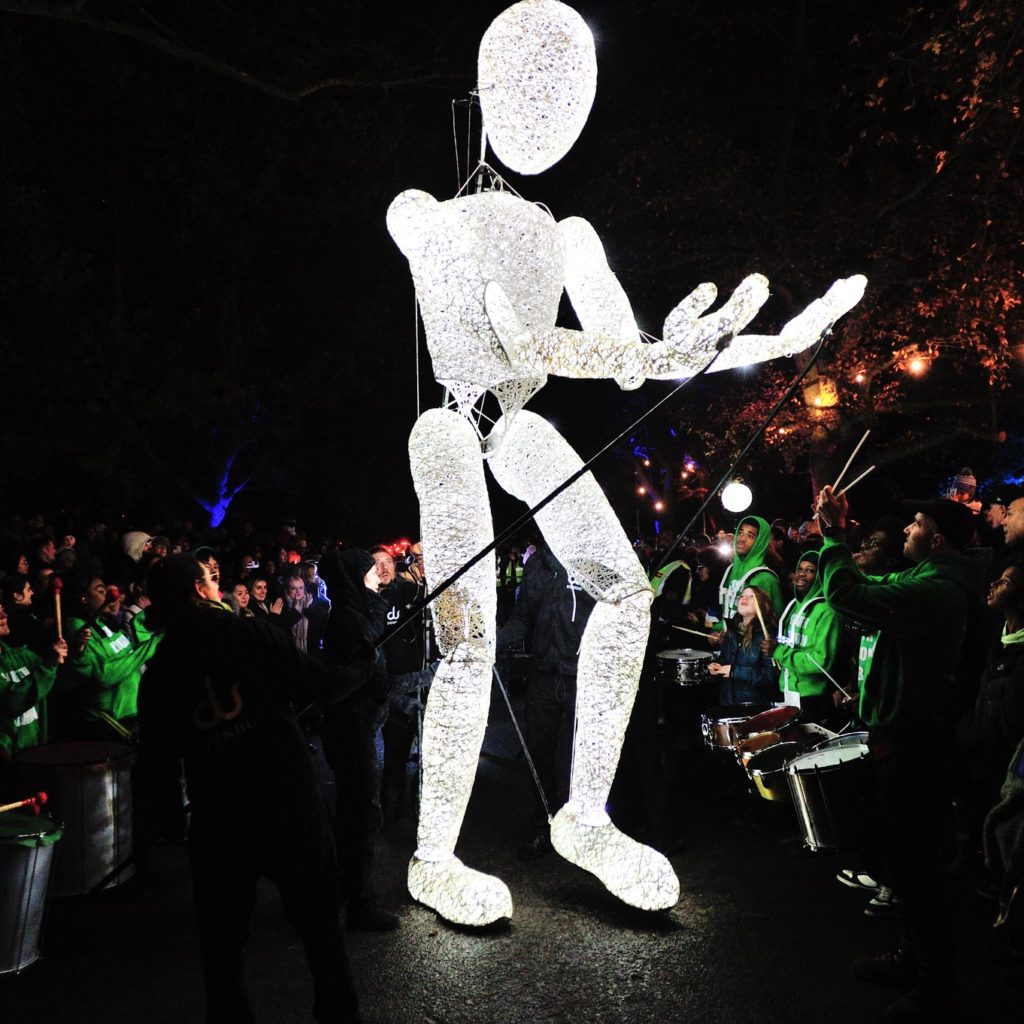 People are gathering around a giant glowing puppet.